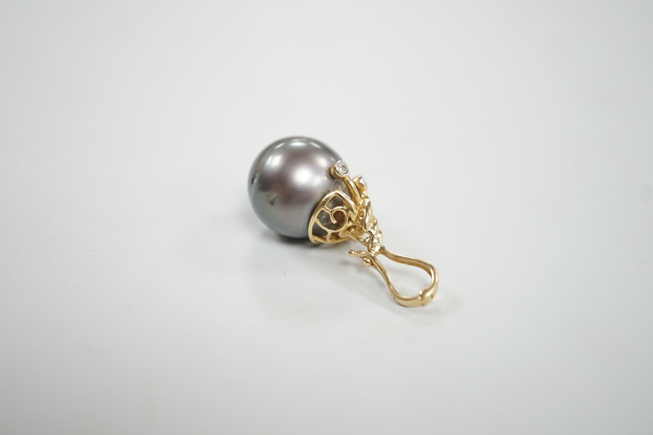 A modern 585 yellow metal, single stone Tahitian pearl and five stone diamond chip set pendant, pearl diameter 13.6mm, 30mm, gross weight 5.4 grams.
